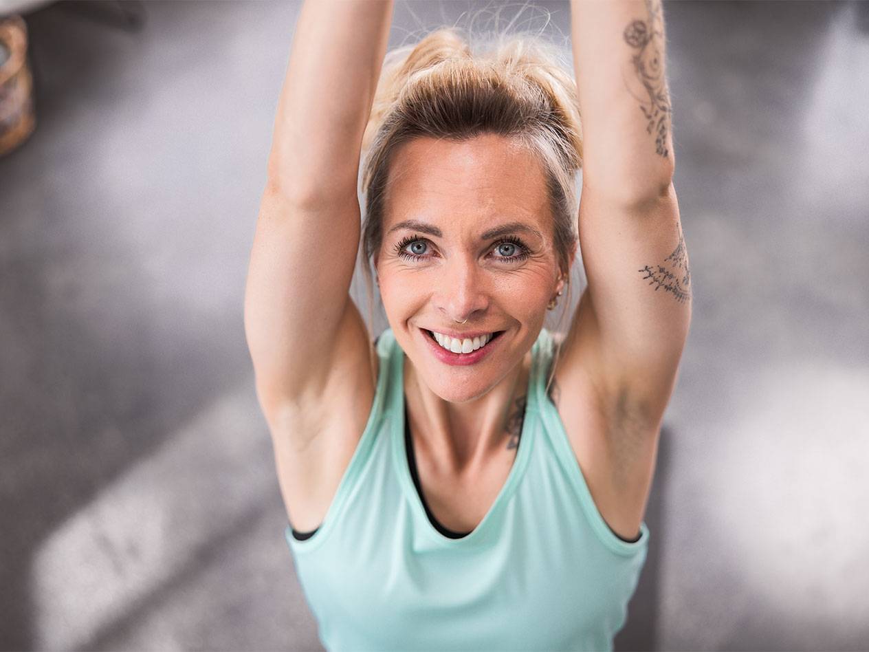 Vaaleahiuksinen nainen vaaleansinisessä topissa hymyilee kameralle.