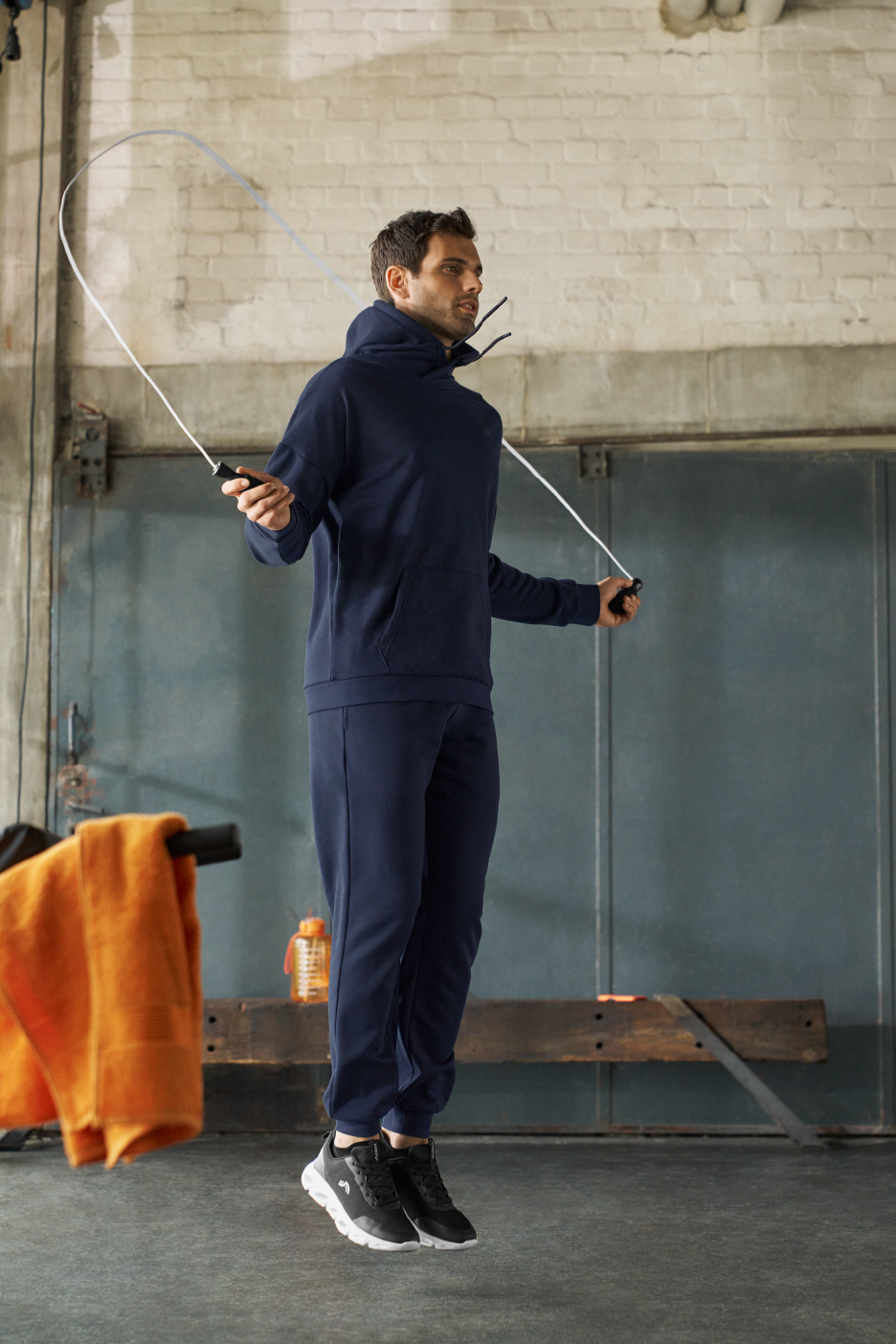 Mies hyppii narua tummansinisessä hupparissa ja collegehousuissa