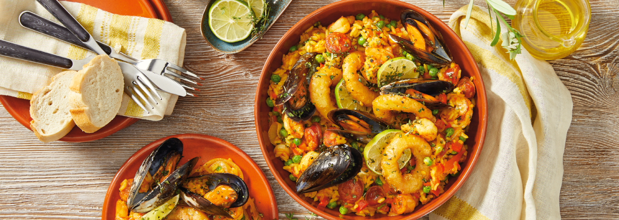 Herkullinen paella-annos, jossa on katkarapuja, simpukoita ja chorizoa, tarjoillaan lämpimän leivän kera.