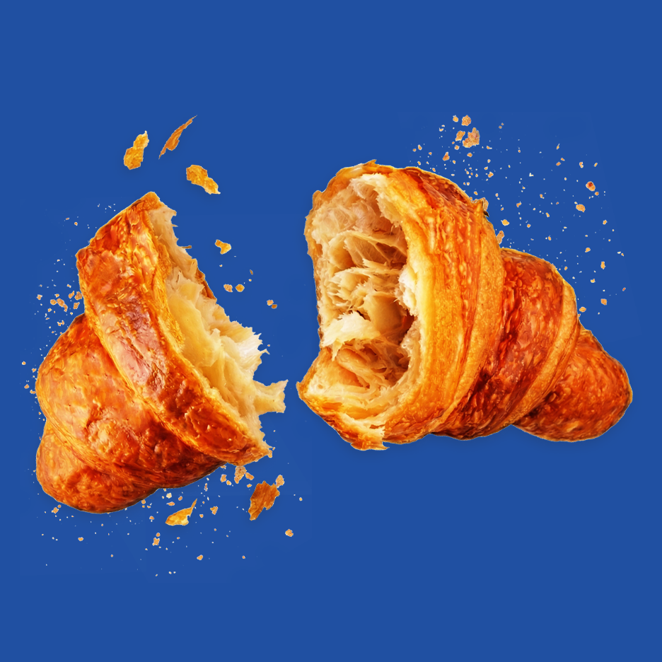 Kaksi puoliksi revittyä croissantia, joiden ympärillä on murusia sinisellä taustalla.