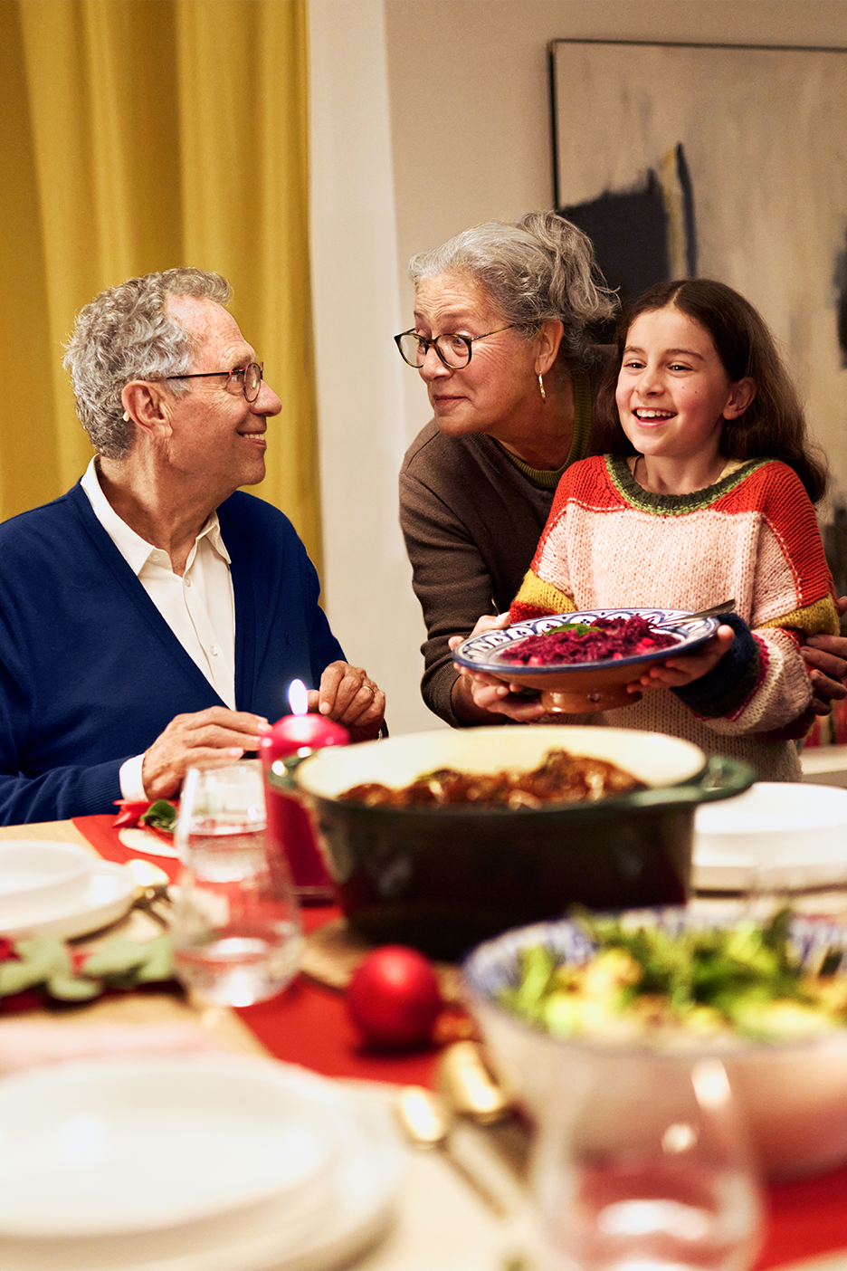Perhe illallispöydässä, tarjolla pataruokaa ja salaattia.