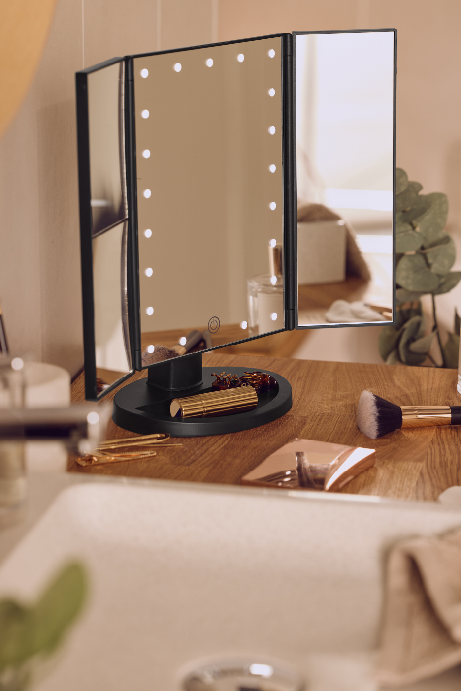 Valaistu meikkipeili ja kosmetiikkaa kylpyhuoneen tasolla.