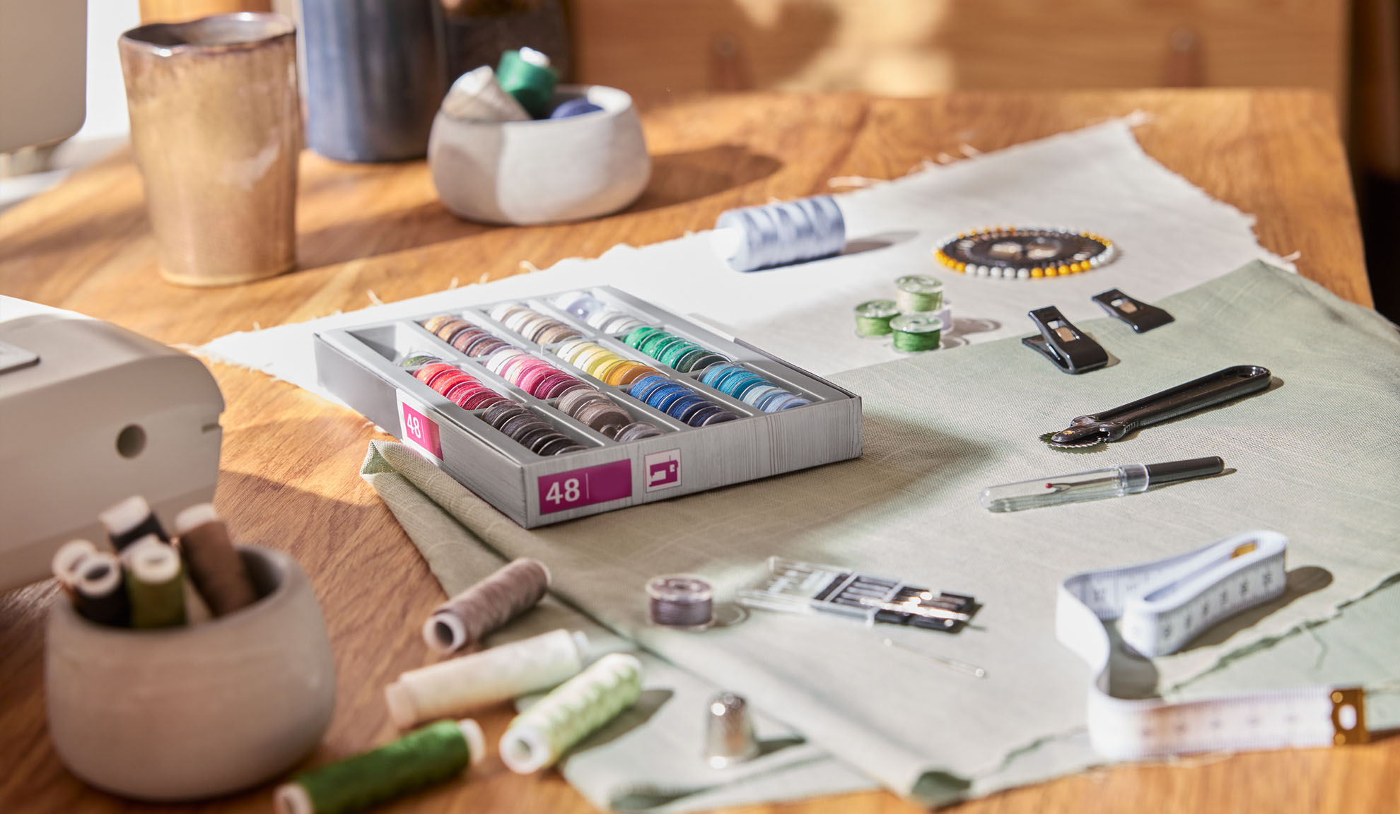 Ompelusetti, jossa laatikko värikkäitä lankoja, ompelukone ja erilaisia työkaluja puupöydällä.