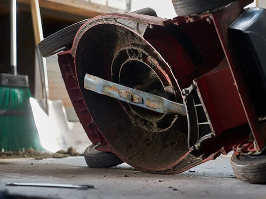 Likainen ruohonleikkuri ylösalaisin, terä näkyvissä