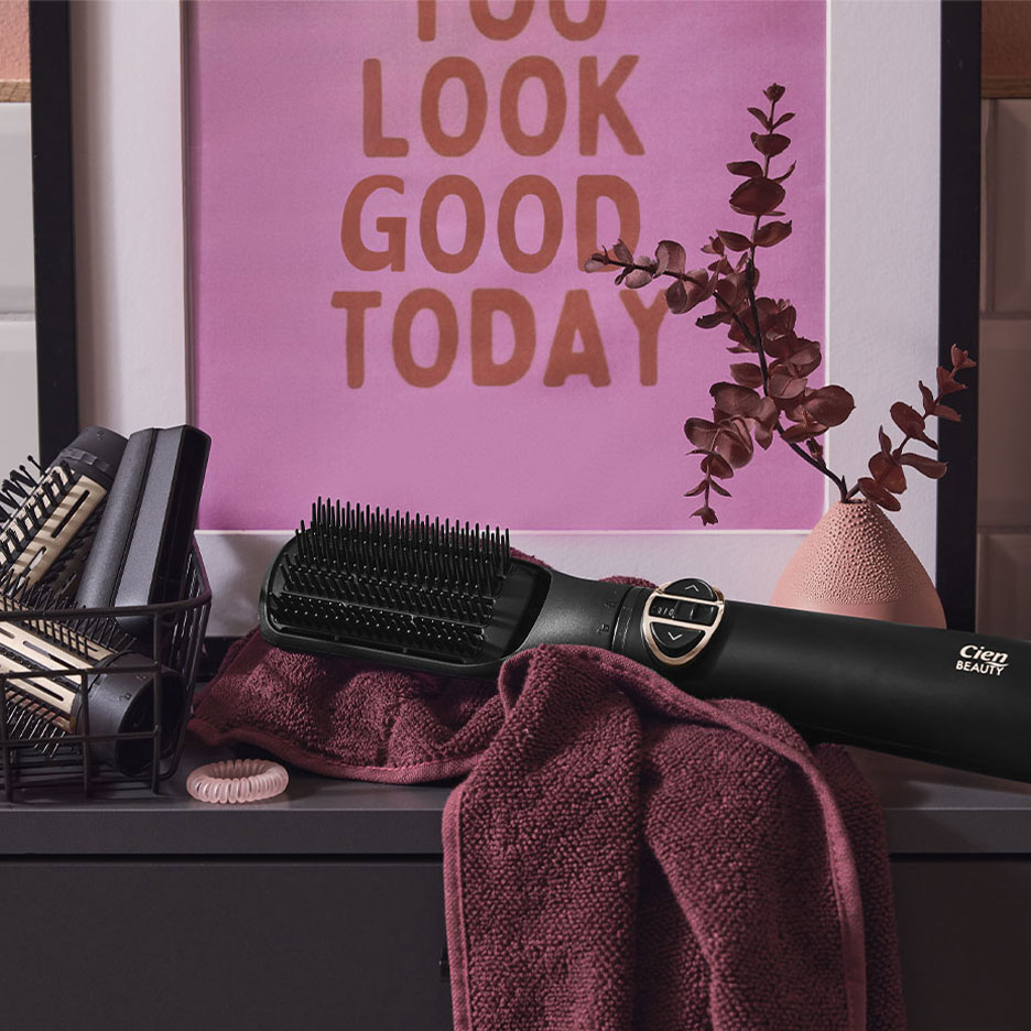 Cien Beauty -hiusten suoristusharja pyyhkeen päällä, hiustarvikkeita ja juliste.