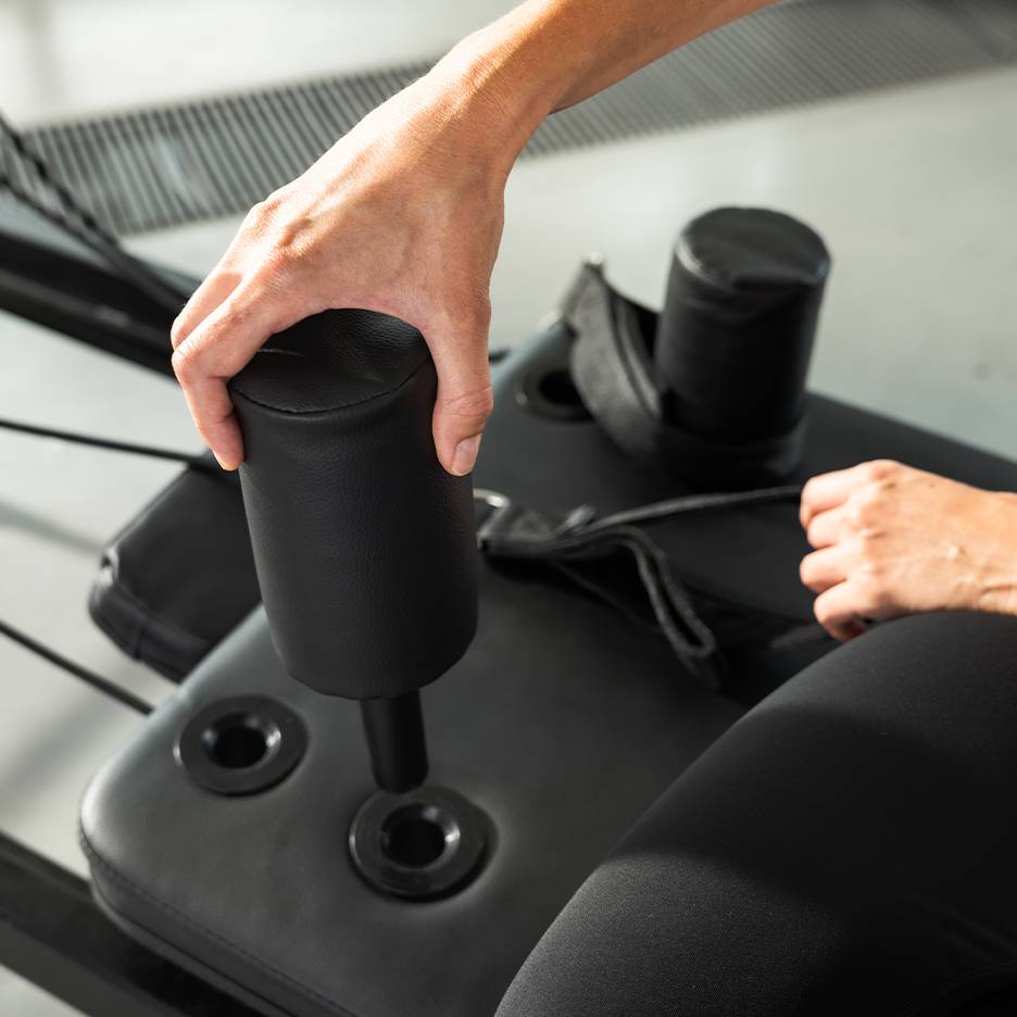Henkilö säätää mustaa pehmustettua kuntolaitetta.
