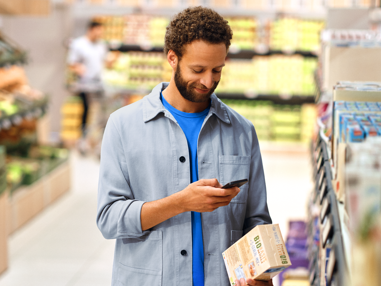 Mies skannaa puhelimellaan tuotetta ruokakaupassa.
