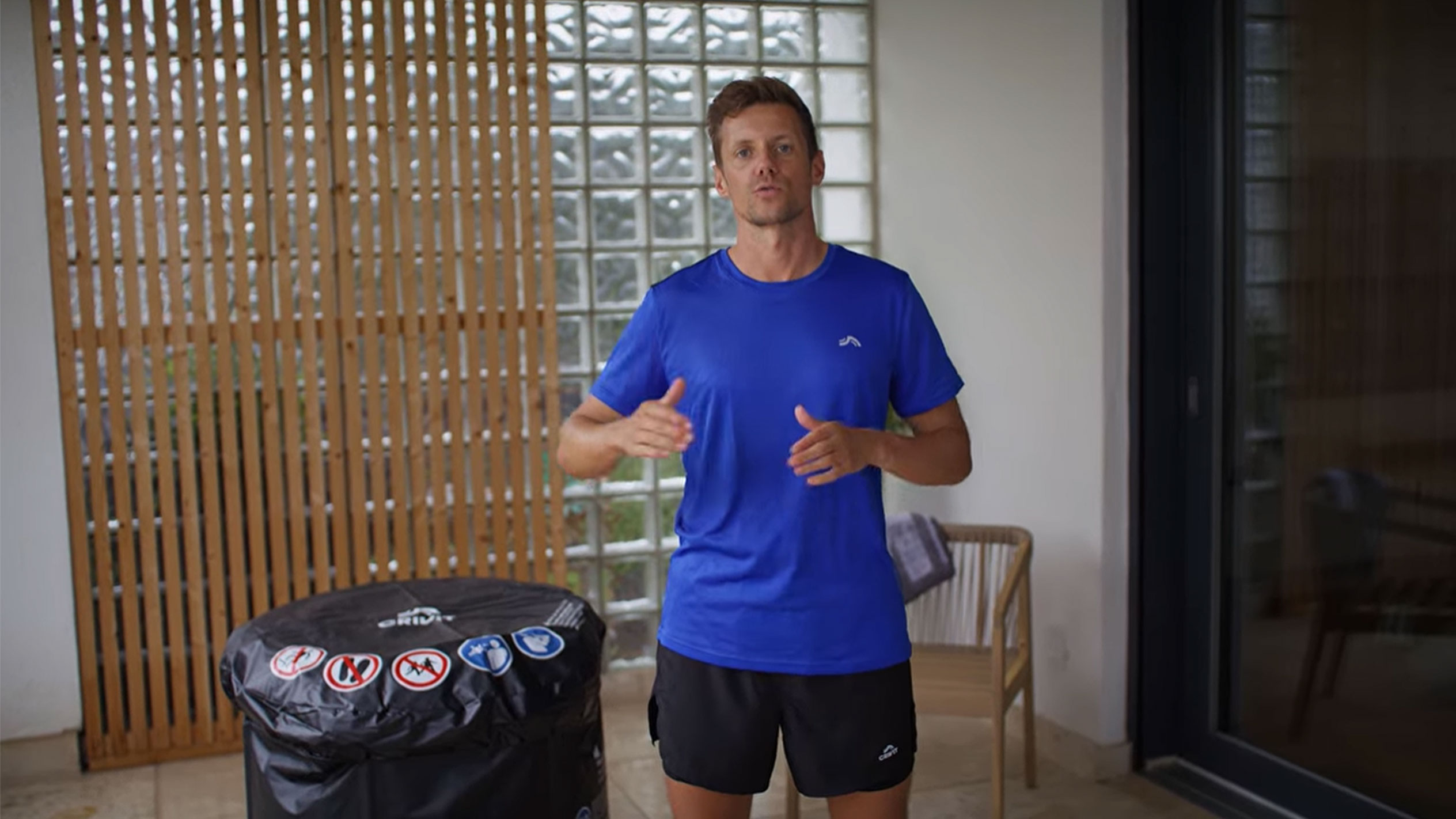 Mies sinisessä T-paidassa ja mustissa shortseissa, mustan porealtaan suojuksen vieressä.