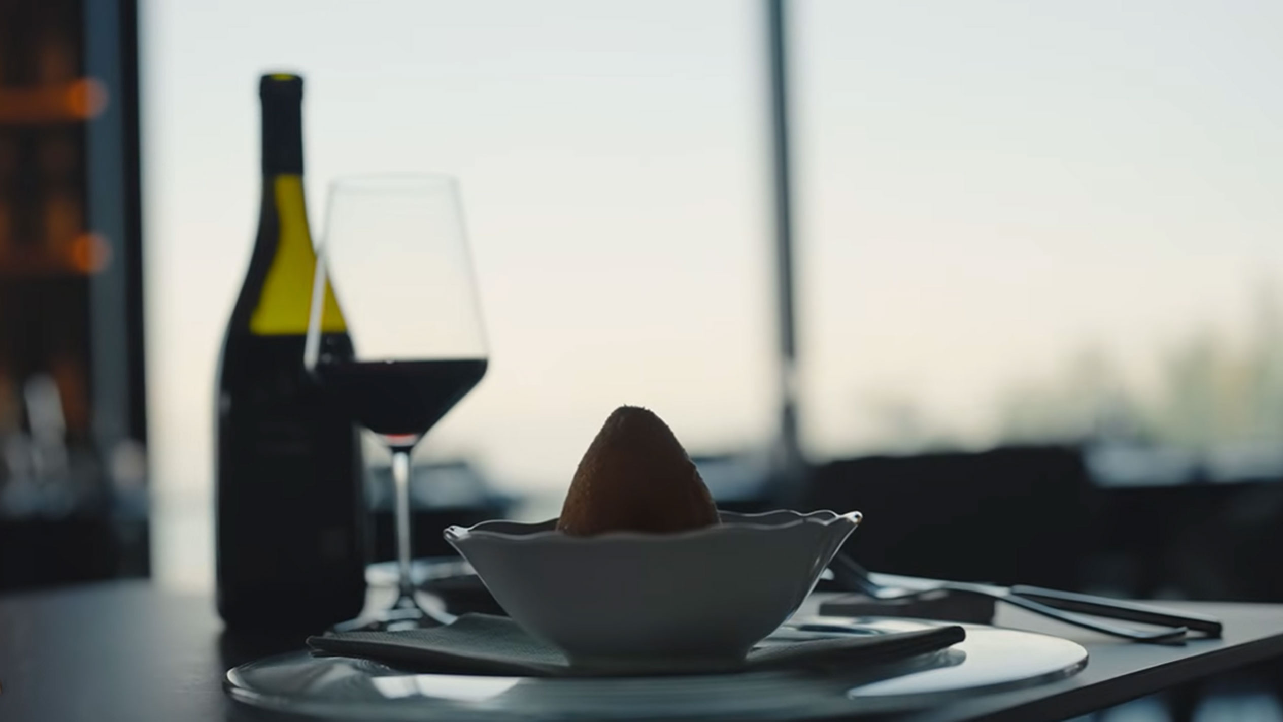 Pullollinen punaviiniä ja lasi yhden arancinon vieressä kulhossa pöydällä.