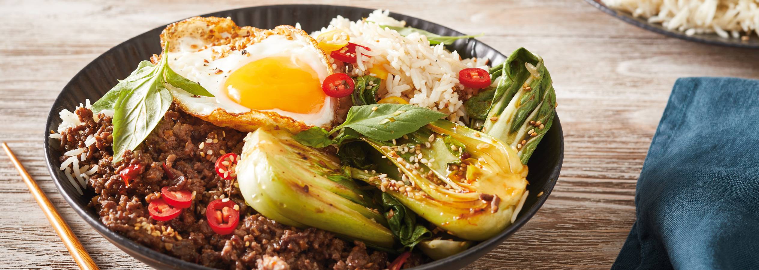 Maukas ja värikäs ruokakulho sisältää naudan jauhelihaa, riisiä, paistettua kananmunaa ja bok choy -vihannesta.