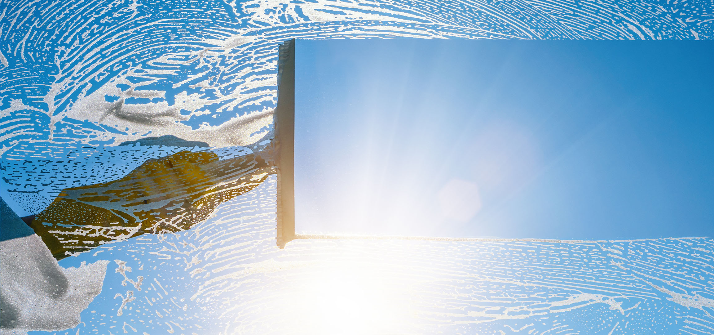 Ikkunanpesua saippuavaahdolla sinistä taivasta vasten.