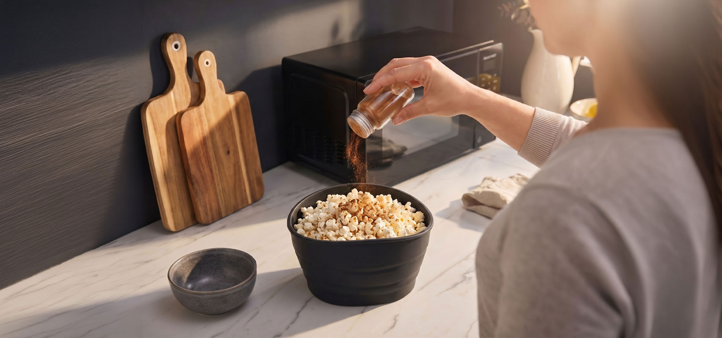 Tekoälyllä luotu: Popcornia mustassa kulhossa maustettuna mausteilla, puisten leikkuulautojen vieressä.