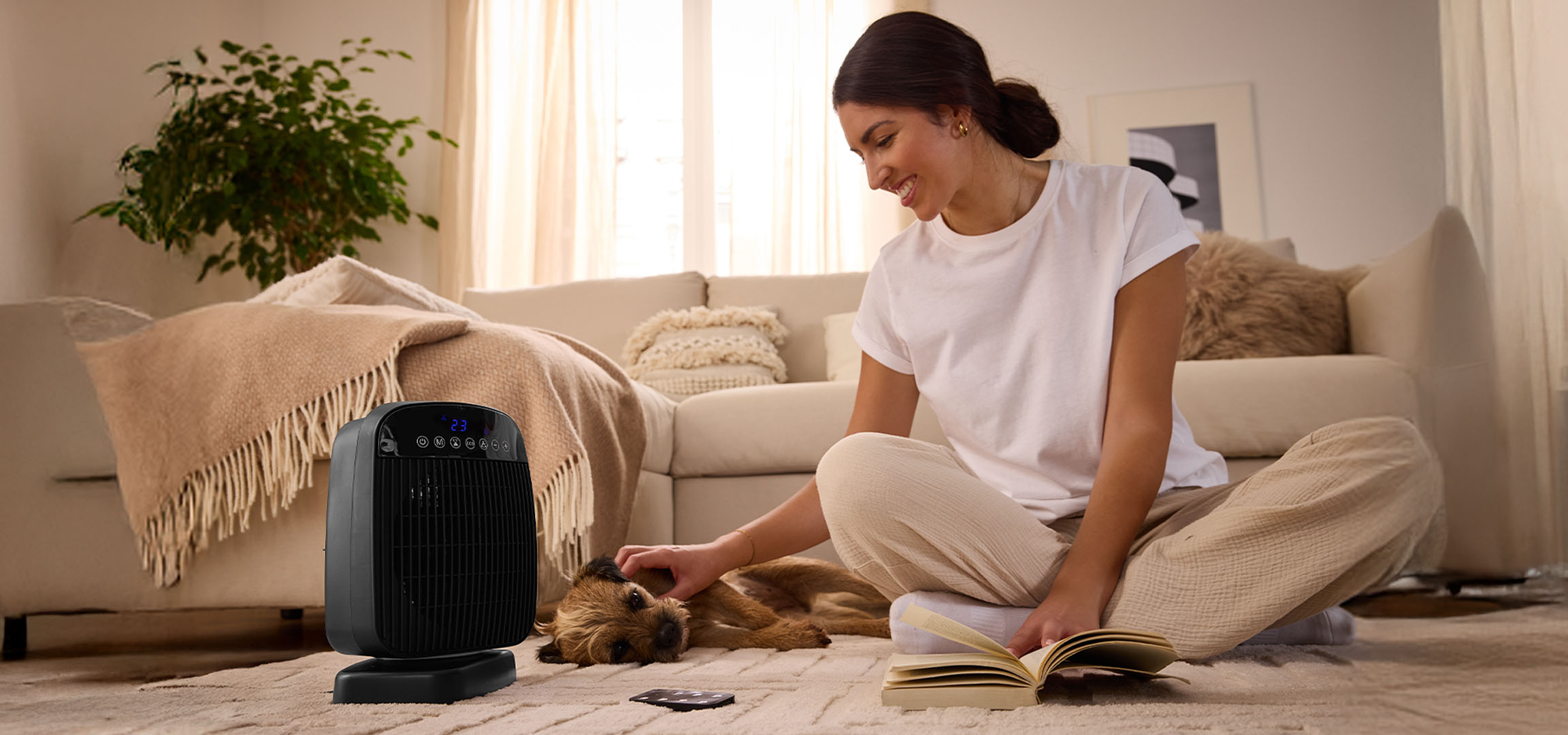 Nainen leikkii koiran kanssa sähkölämmittimen vieressä olohuoneessa.