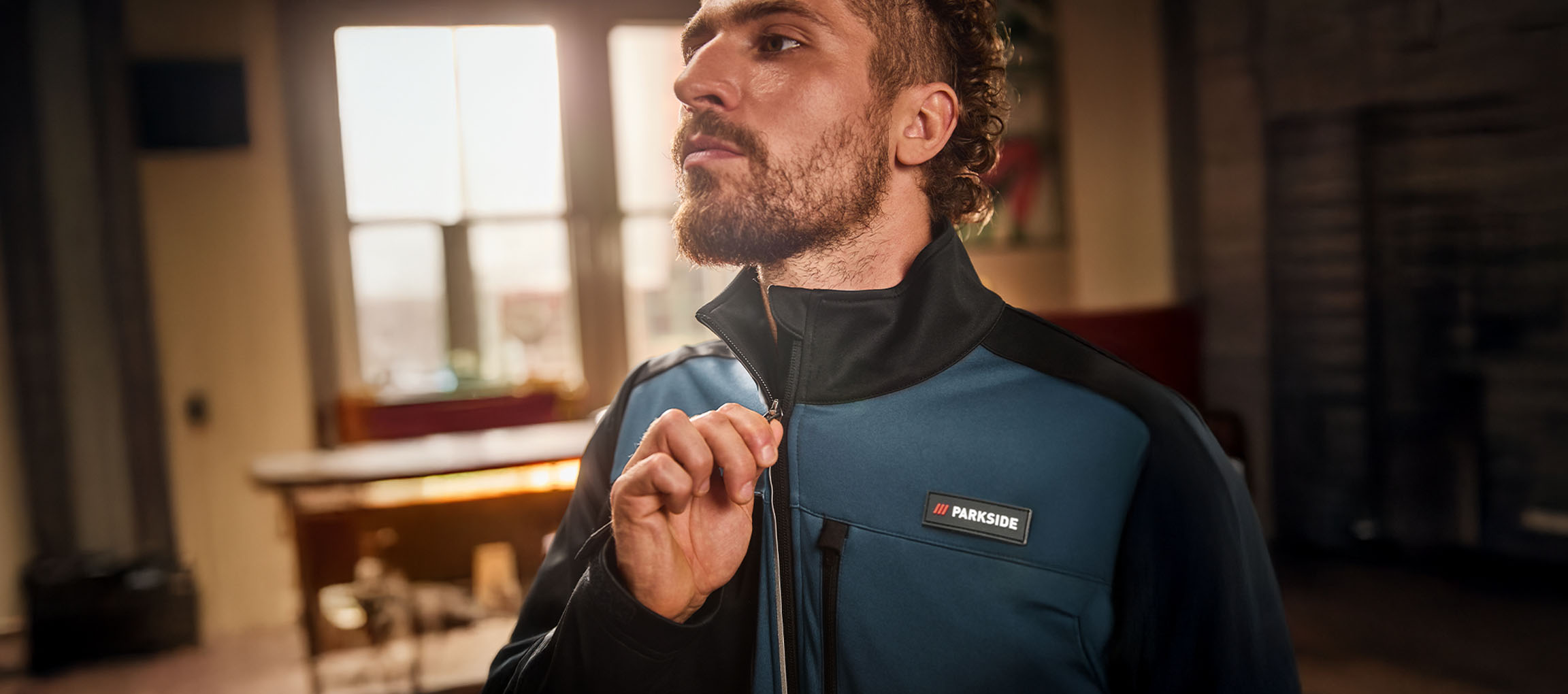 Mies sinimustassa Parkside-työtakissa vetoketjua sulkemassa