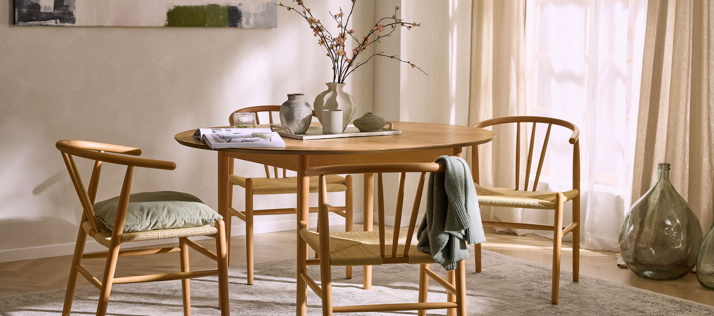 Ruokailutila pyöreällä puupöydällä, puutuoleilla, joissa on köysi-istuimet, ja koristeellisilla maljakoilla.