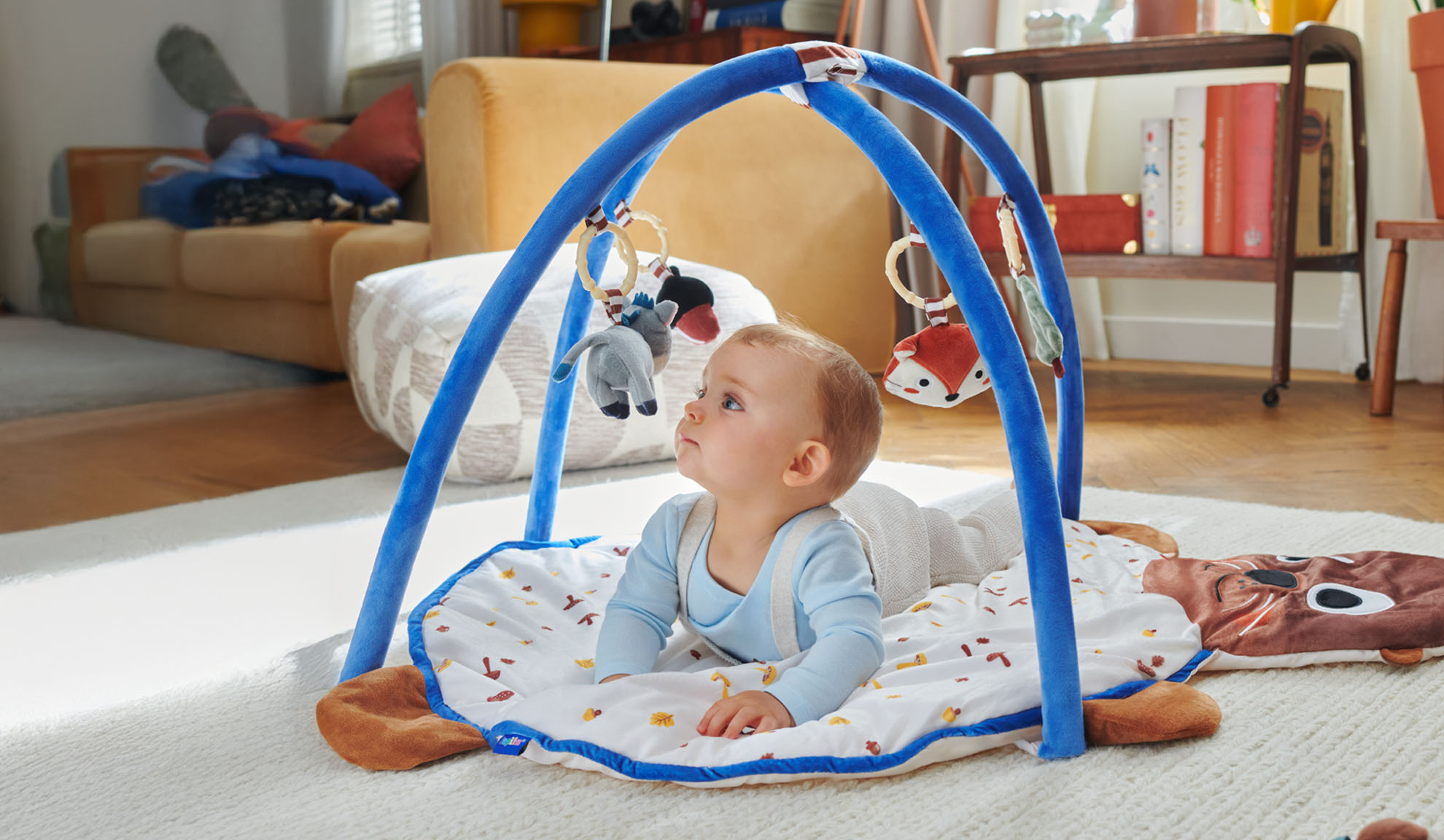 Vauva leikkii Tiny Love -leikkimatolla, jossa on eläinhahmoinen kaari.