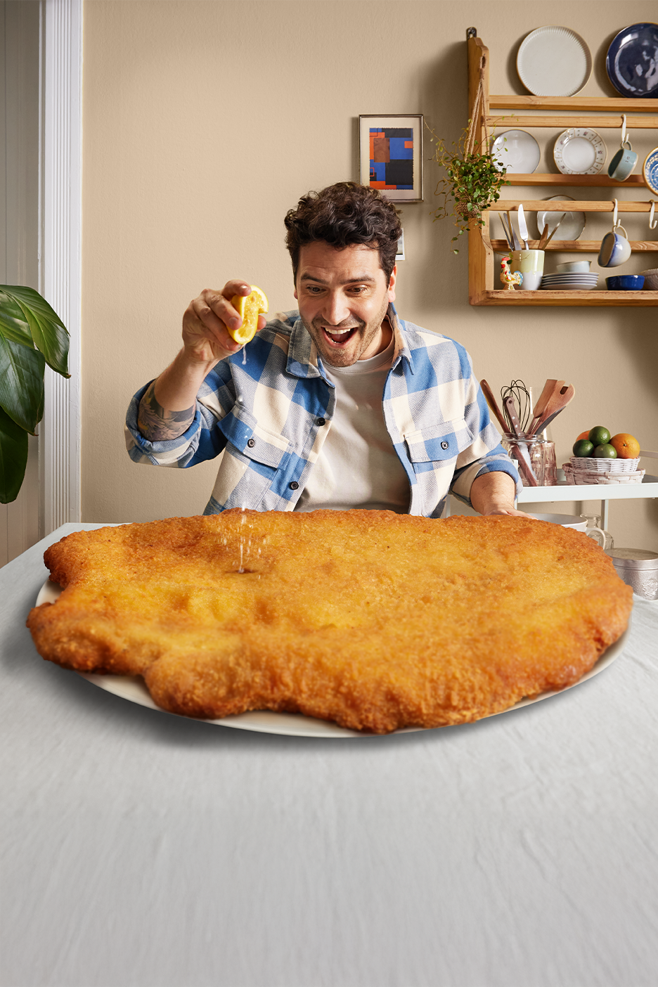 Mies puristaa sitruunaa valtavan leikkeen päälle keittiössä.