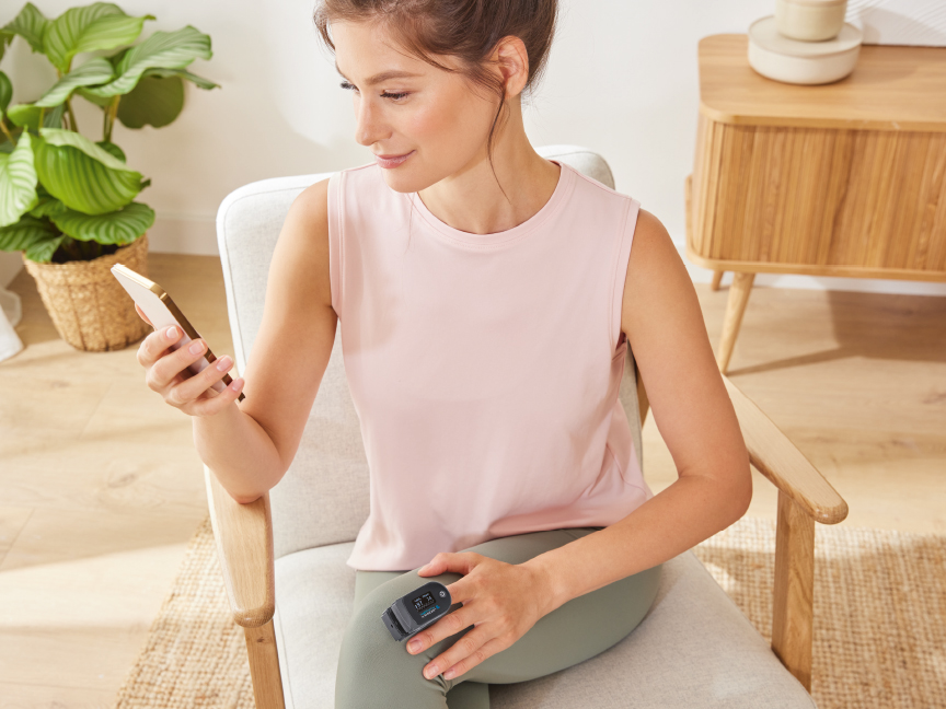 Nainen tarkistaa älypuhelimestaan terveystietoja, joita on mitattu ranteeseen kiinnitetyllä Withings-aktiivisuusmittarilla.