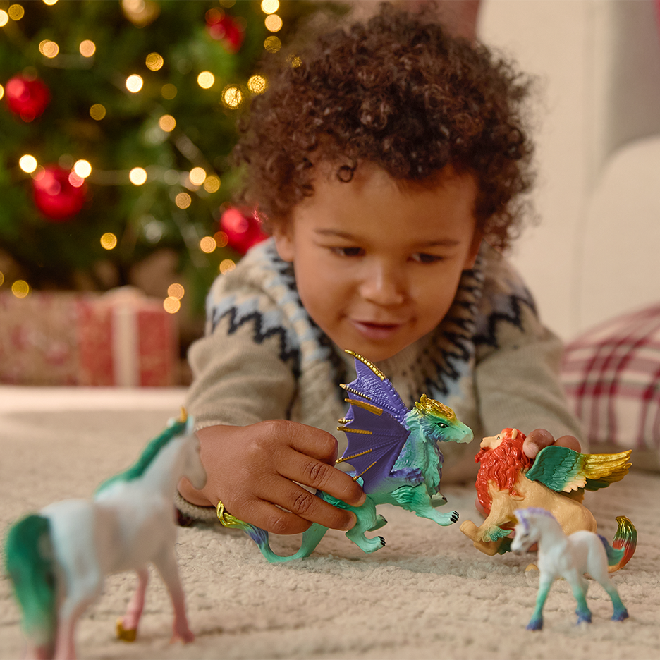 Lapsi leikkii fantasiatoimintahahmoilla joulukuusen edessä.