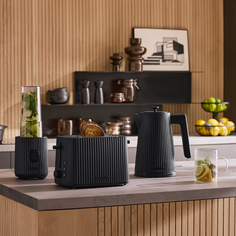 Musta vedenkeitin, leivänpaahdin ja tehosekoitin keittiön työtasolla.