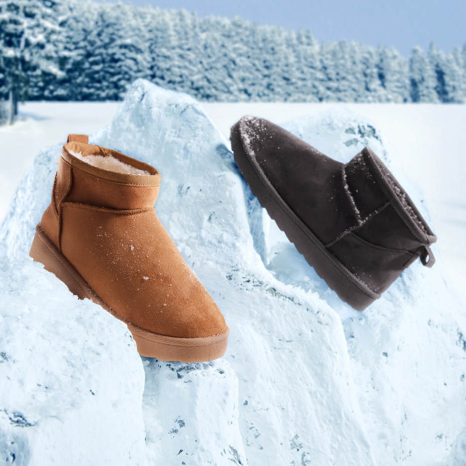 Ruskeat ja mustat talvikengät lumisessa maisemassa