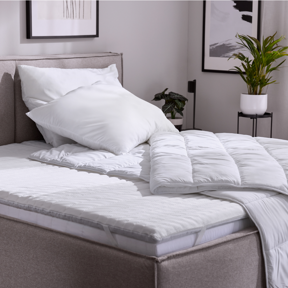 Valkoiset tyynyt, peitto ja patjansuojus sängyssä, makuuhuoneen sisustus.