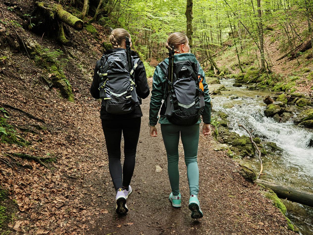 Kaksi naista Crivit-reppuineen vaeltaa metsäpolulla.