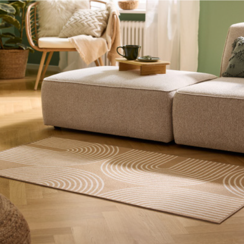 Olohuoneen sisustus beigellä sohvalla, puulattialla ja beigellä matolla, jossa on valkoisia kaaria.